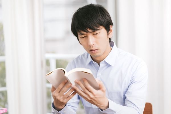 本で調べる男性