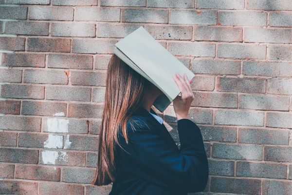 女性が本を顔にかぶせている